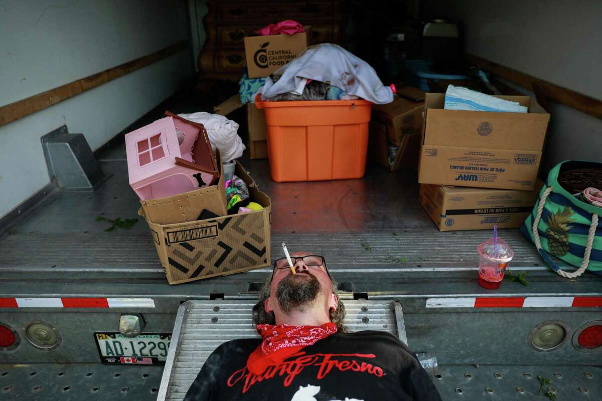 A man takes a cigarette break after retrieving belongings from the Fresno house he and his family were evicted from.