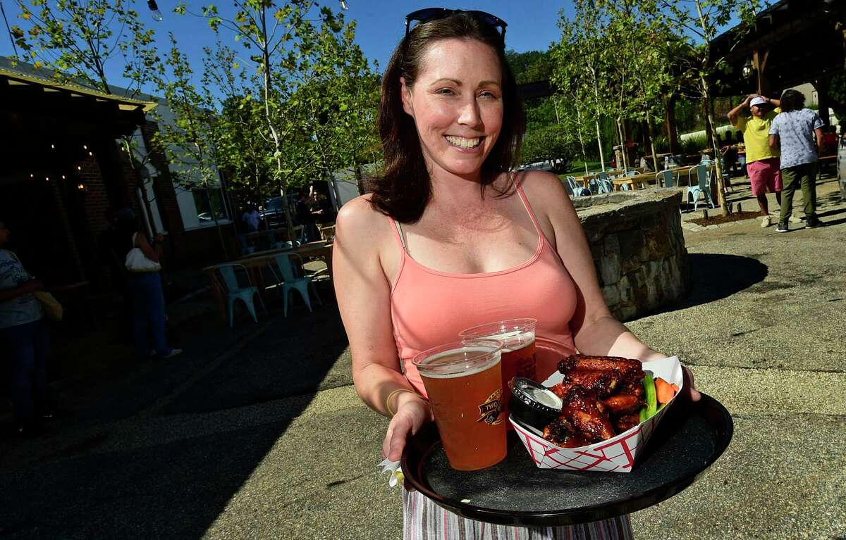 314 Beer Garden Event and Social Media Manager Jennifer Sandusky serves up beer and Mole Wings at their grand opening Saturday, September 25, 2021, in Norwalk, Conn.