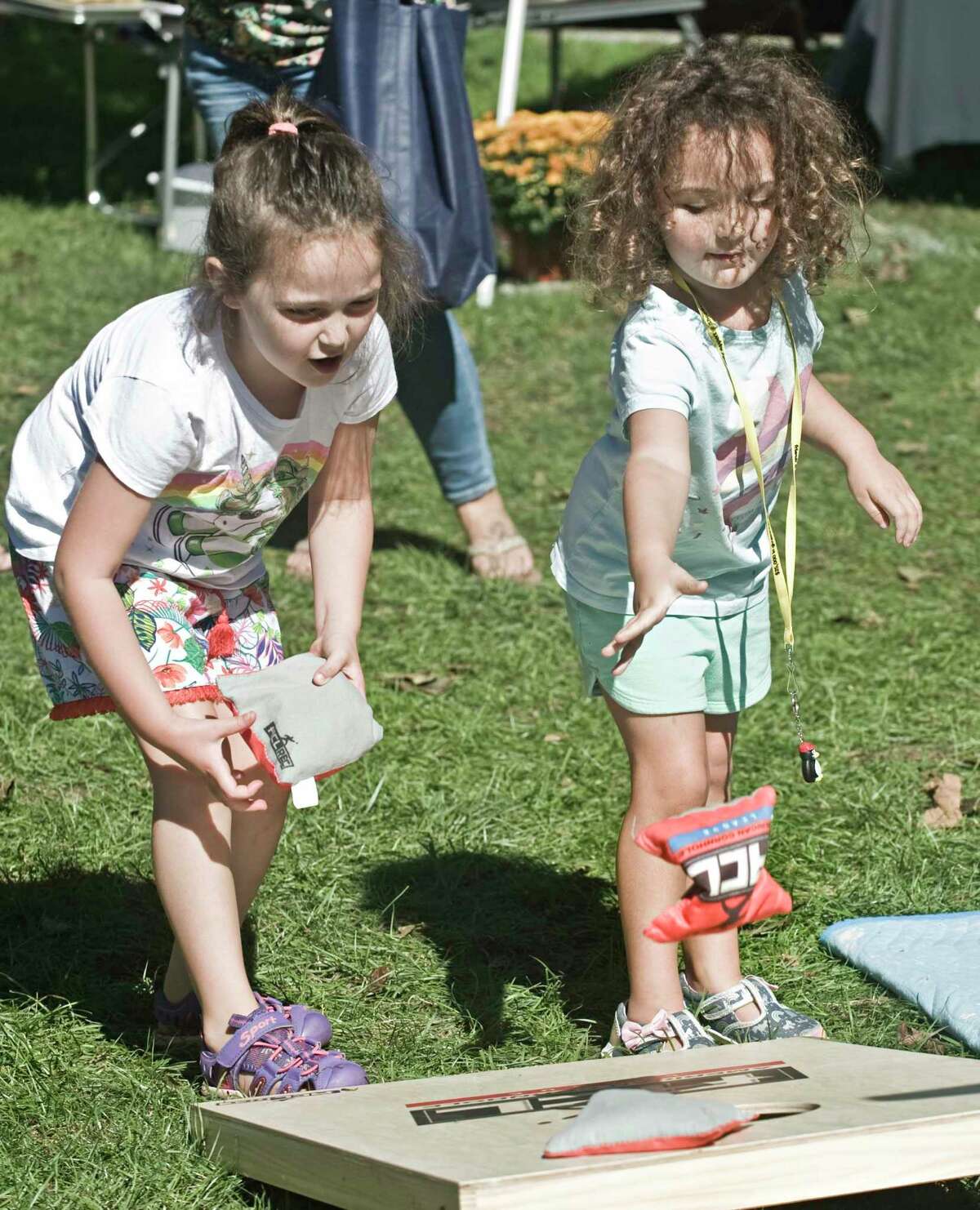 Taylor DeDiase, 6 of Brookfield, and her sister Remi, 4, doing the bean bag game at the Apple Festival on the New Milford town green. Saturday, Sept. 25, 2021