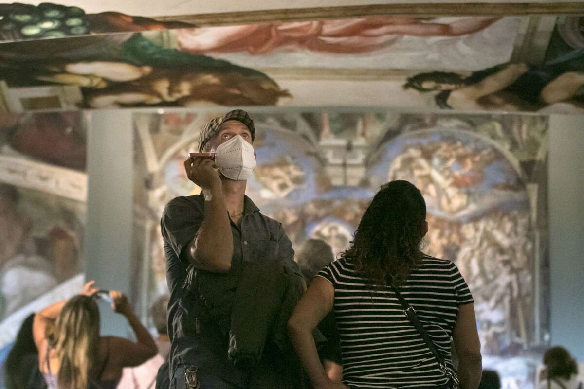 A visitor listens to a taped guide about the paintings while viewing an art installation recreating the Sistine Chapel in an exhibition at St. Mary's Cathedral, San Francisco, on September 24, 2021.