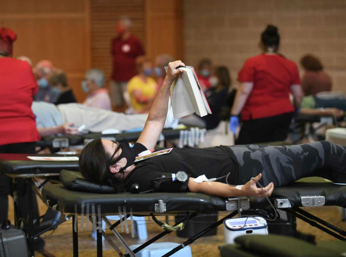 Greenwich resident Mary Figgie reads a book while donating blood at the American Red Cross blood drive at Temple Sholom in Greenwich, Conn. Monday, Aug. 2, 2021.