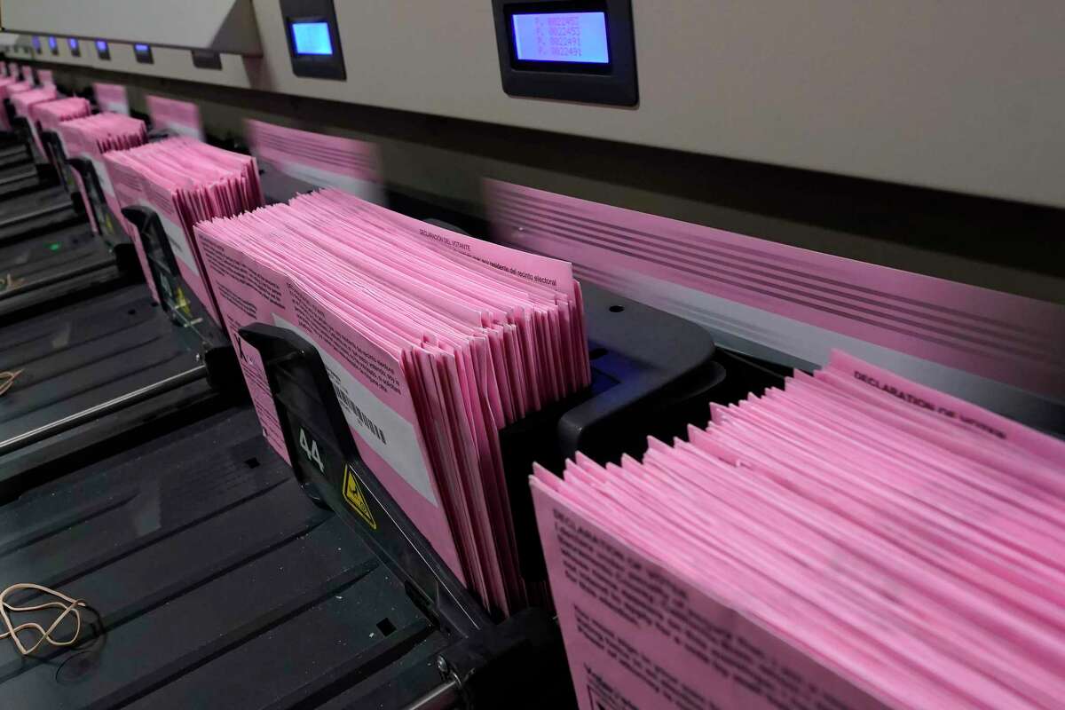 Mail-in ballots run through a sorting machine at the Sacramento County Registrar of Voters office in Sacramento.