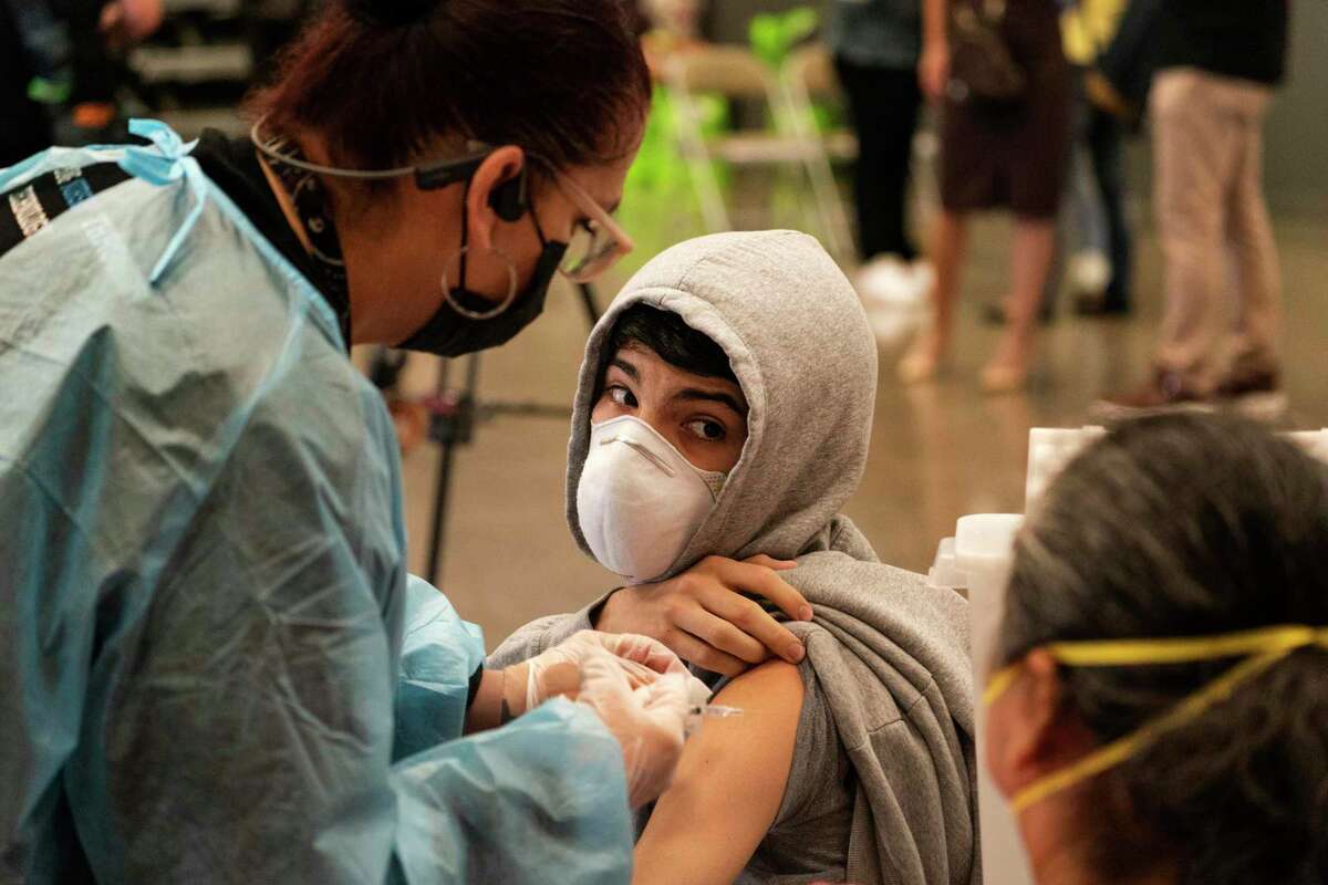 A student looks back at his mother as he is vaccinated at a clinic for students 12 and older in San Pedro (Los Angeles County). The surge is subsiding in California.