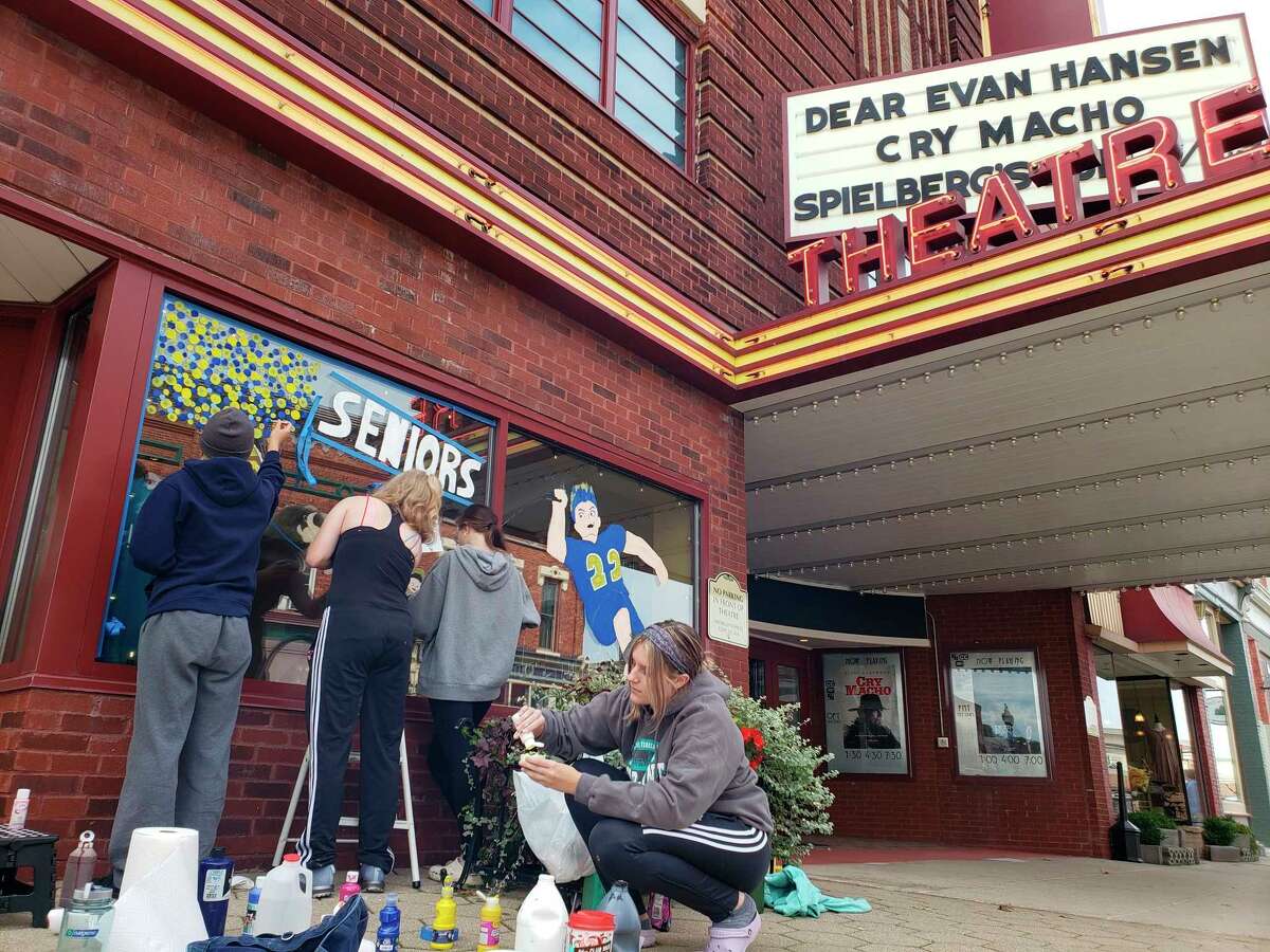Manistee High School seniors paint the Vogue Theatre's window on Sunday afternoon, an annual homecoming tradition. (Arielle Breen/News Advocate)