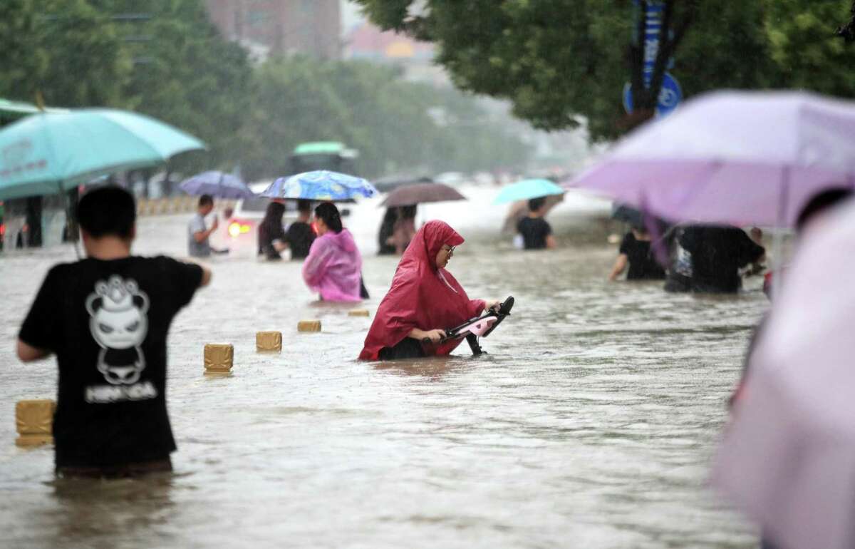 People walk in the flooded road after record downpours in Zhengzhou, in central China’s Henan province, on July 20, 2021.