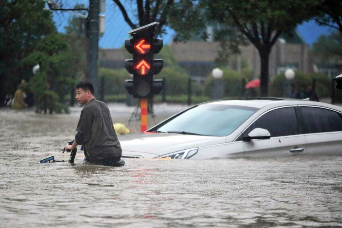 A man walks a bike along a flooded road after record downpours in Zhengzhou city in central China’s Henan province Tuesday, July 20, 2021.