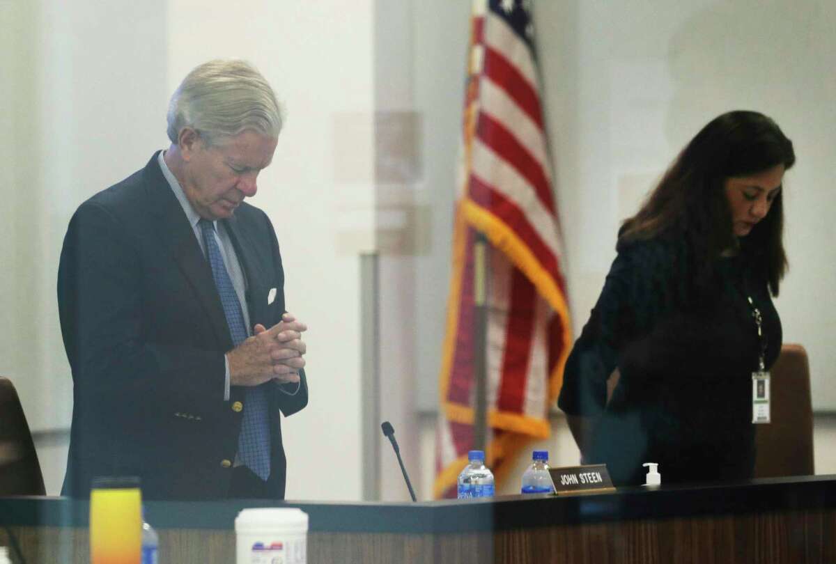 CPS Energy board member John Steen bows in prayer as officials meet for the utility's monthly board meeting. Board members approved the proposed rate hike before going to the city council.
