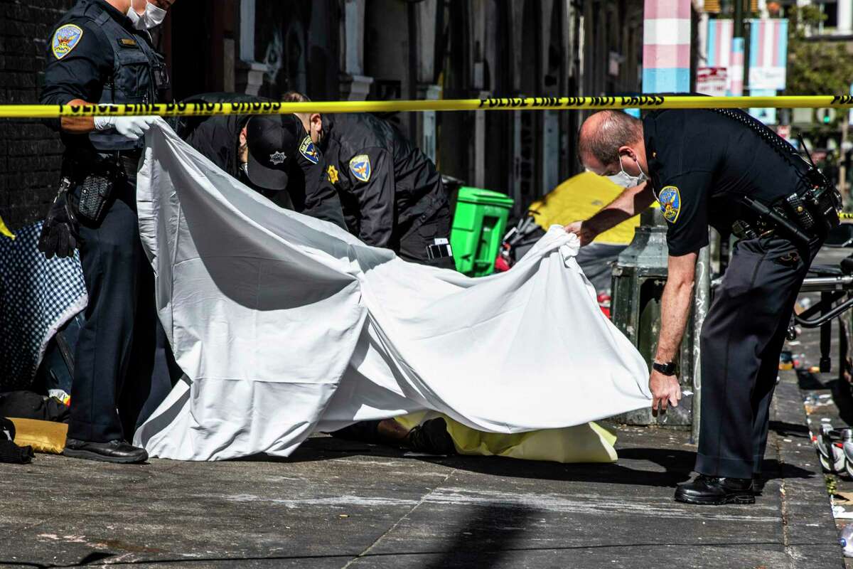 在旧金山金门大道和琼斯街的拐角处，法医小组的成员正在搬运一具可能是吸毒过量的受害者的尸体，旧金山警察拿着一个尸袋。
