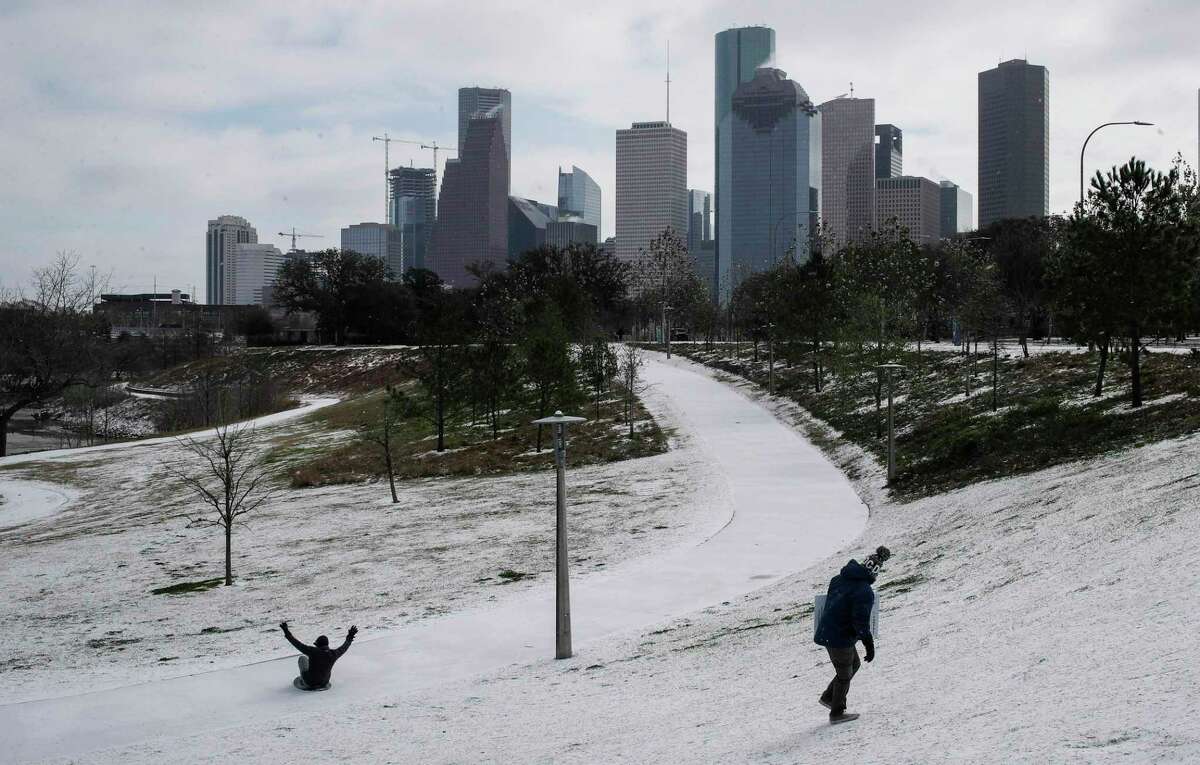 Chris Martinez, right, looks back at a man sliding down a hill as a winter storm hits Houston on Monday, Feb. 15, 2021, at Buffalo Bayou Park in Houston.