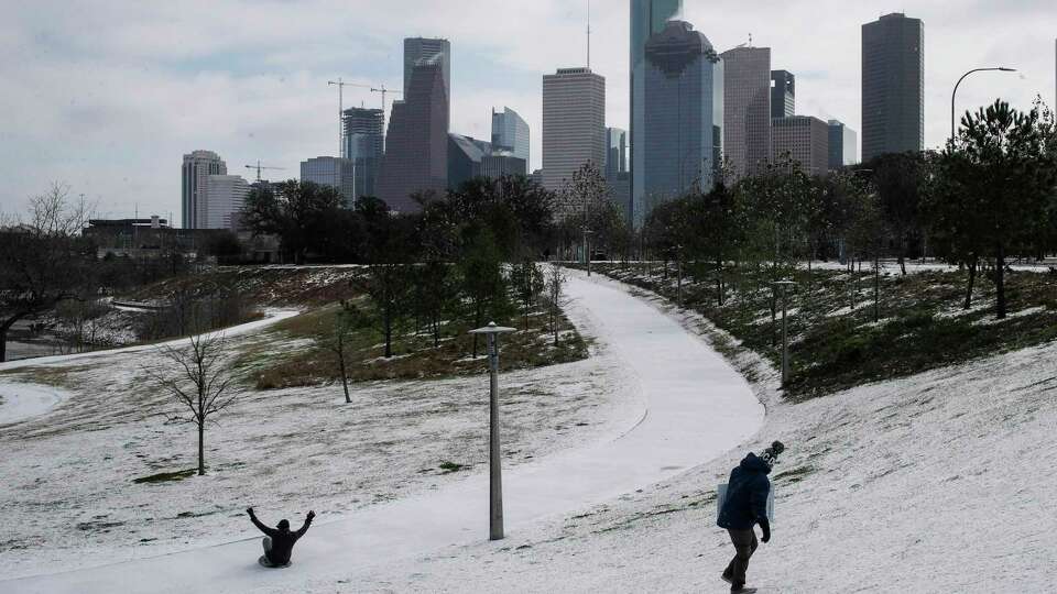 Chris Martinez, right, looks back at a man sliding down a hill as a winter storm hits Houston on Monday, Feb. 15, 2021, at Buffalo Bayou Park in Houston.