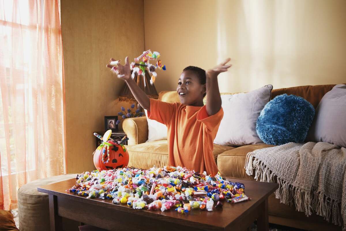 Pictured is a boy tossing Halloween candy into the air.