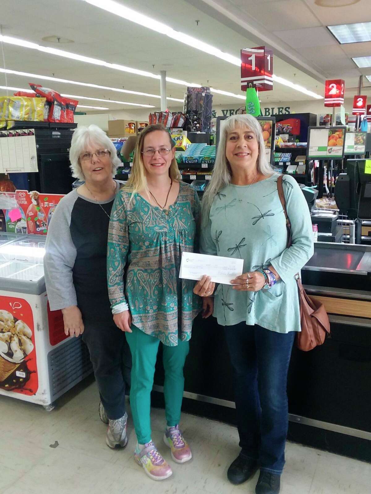 Bread of Life Pantry director Lynne Mills, far right, accepts a donation of $690 from Houseman's Labor Day "$1 at check out" campaign. Pictured with Mills are Houseman's associates Rebecca French (left) and Cassidy Holtrust.