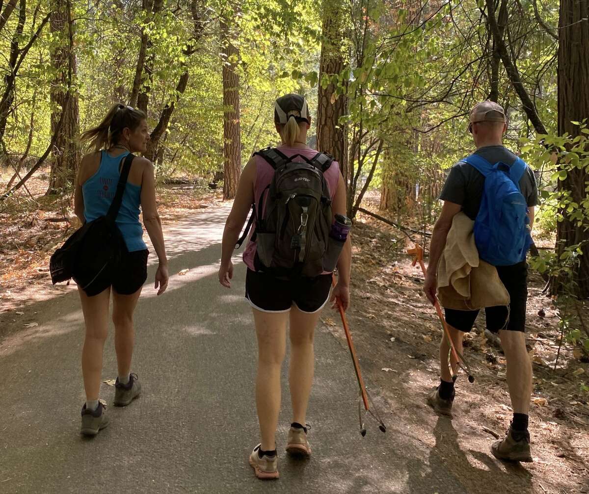 Three Yosemite Facelift volunteers pick up trash along a trail in the park.