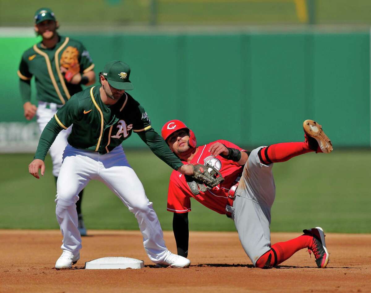 Alex Blandino (0) is tagged out by Pete Kozma (38) on a steal attempt in the first inning as the Oakland Athletics played the Cincinnati Reds at Hohokam Stadium in Mesa, Ariz., on Monday, March 1, 2021.