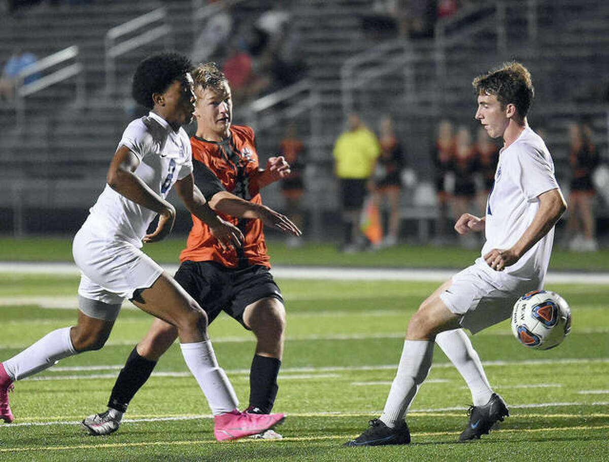 Edwardsville’s Evan Moore blasts the game-winning goal past a pair of Belleville East defenders in the second overtime Thursday at the District 17 Sports Complex.