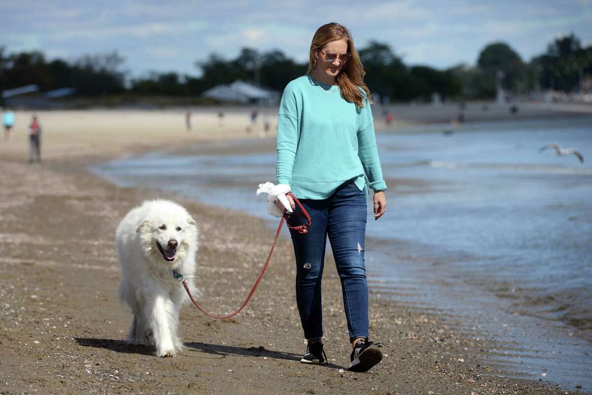 Lisa Larkin walks with her dog Harvey at Penfield Beach, in Fairfield, Conn. Oct. 1, 2021.