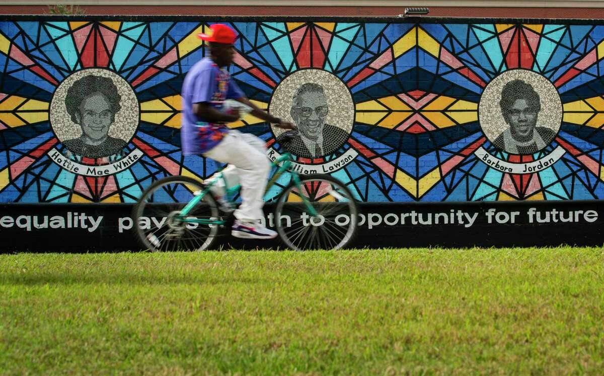 A cyclist travels north up the Columbia Tap Rail-Trail past the "Sacred Struggles/Vibrant Justice" mural honoring Houston civil rights leaders, Thursday, Sept. 30, 2021, just south of Texas Southern University in Houston. U.S. Rep. Sheila Jackson Lee would lose downtown and the entire Third Ward area if a proposed redrawn District 18 map is accepted by the current legislature.