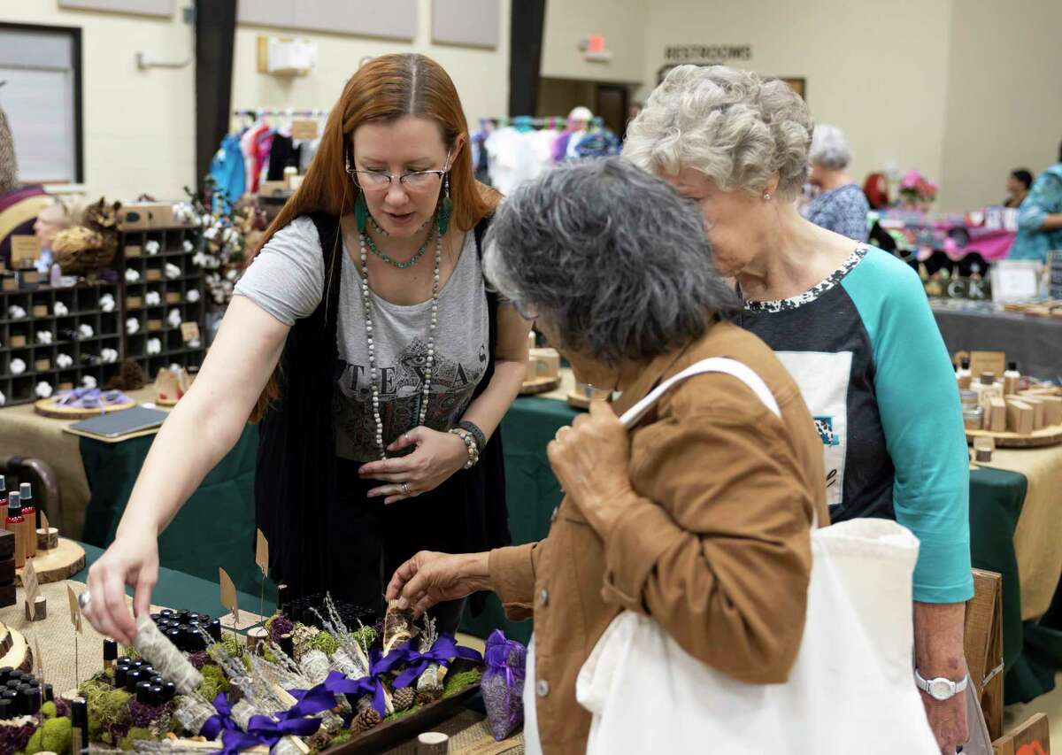 Jaimi Edgmon, center, describes her handmade natural products from Cranky Owl during the Deck the Halls Fall and Christmas Market at First Baptist Church, Friday, Oct. 1, 2021, in downtown Conroe. The event lasted for two days featuring many local homecraft makers.