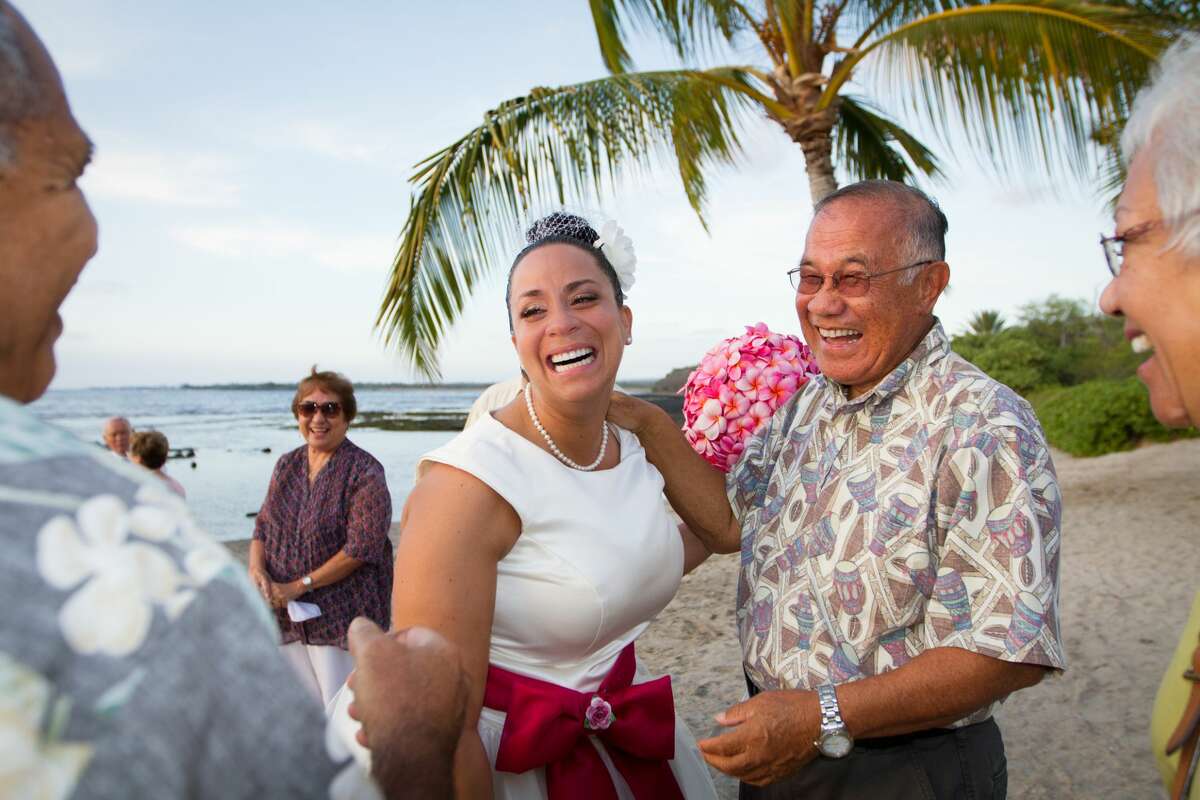 Bride laughing it up with friends and family after Hawaiian beach ceremony.