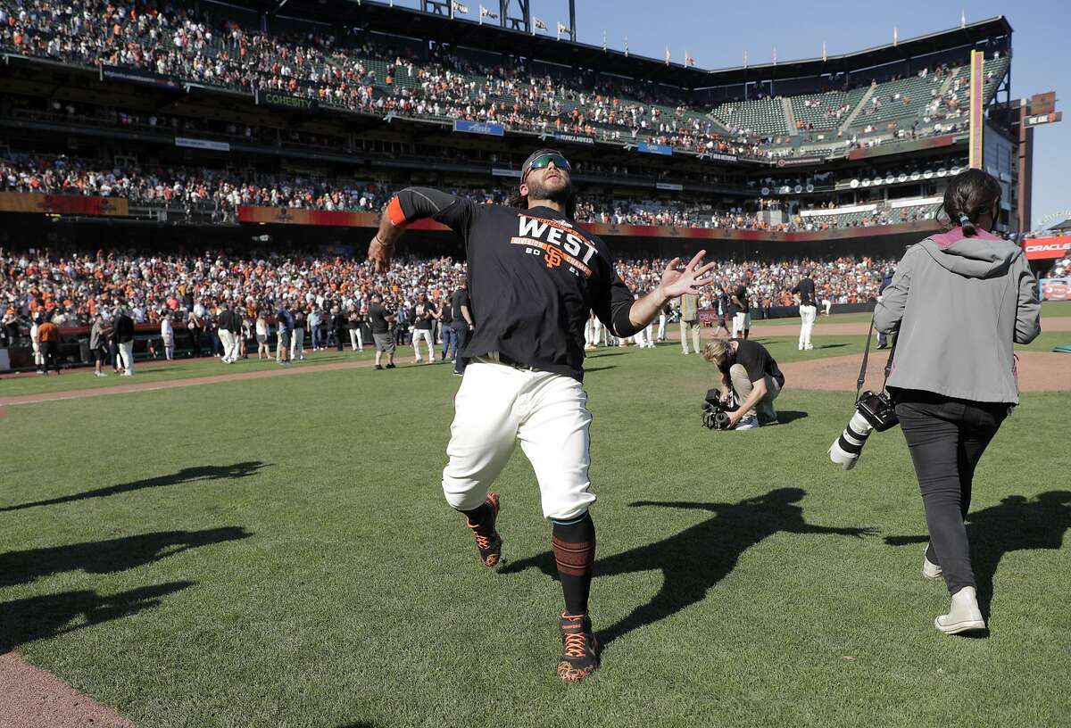Brandon Crawford throws a ball to the fans as the San Francisco Giants celebrate on the field after they defeated the San Diego Padres 11-4 to win the National League West at Oracle Park in San Francisco, Calif., on Sunday, October 3, 2021.
