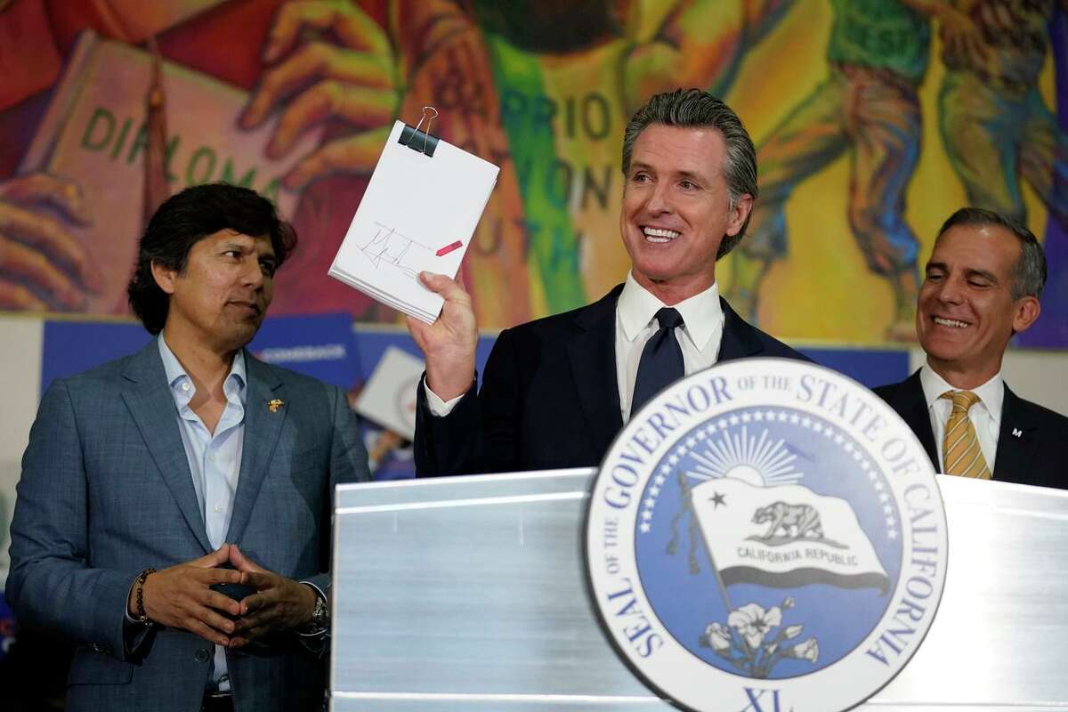 Gov. Gavin Newsom rejoices after signing the California Comeback Plan in July alongside Los Angeles City Council Member Kevin de Leon (left) and Mayor Eric Garcetti.