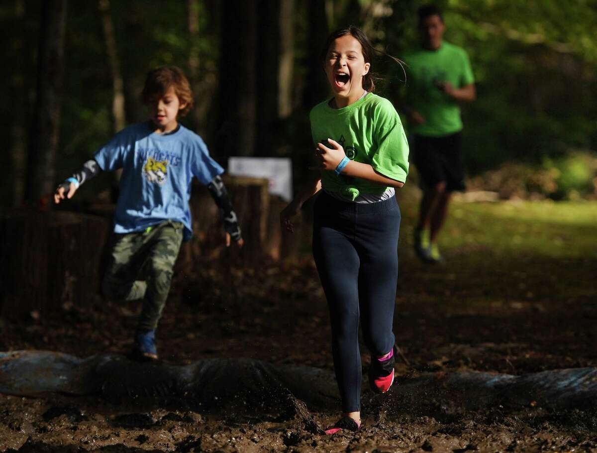 Runners cross the first of several mud pits during the ninth annual Muddy Up 5k run put on by the Boys and Girls Club of Greenwich at Camp Simmons in Greenwich on Sunday.