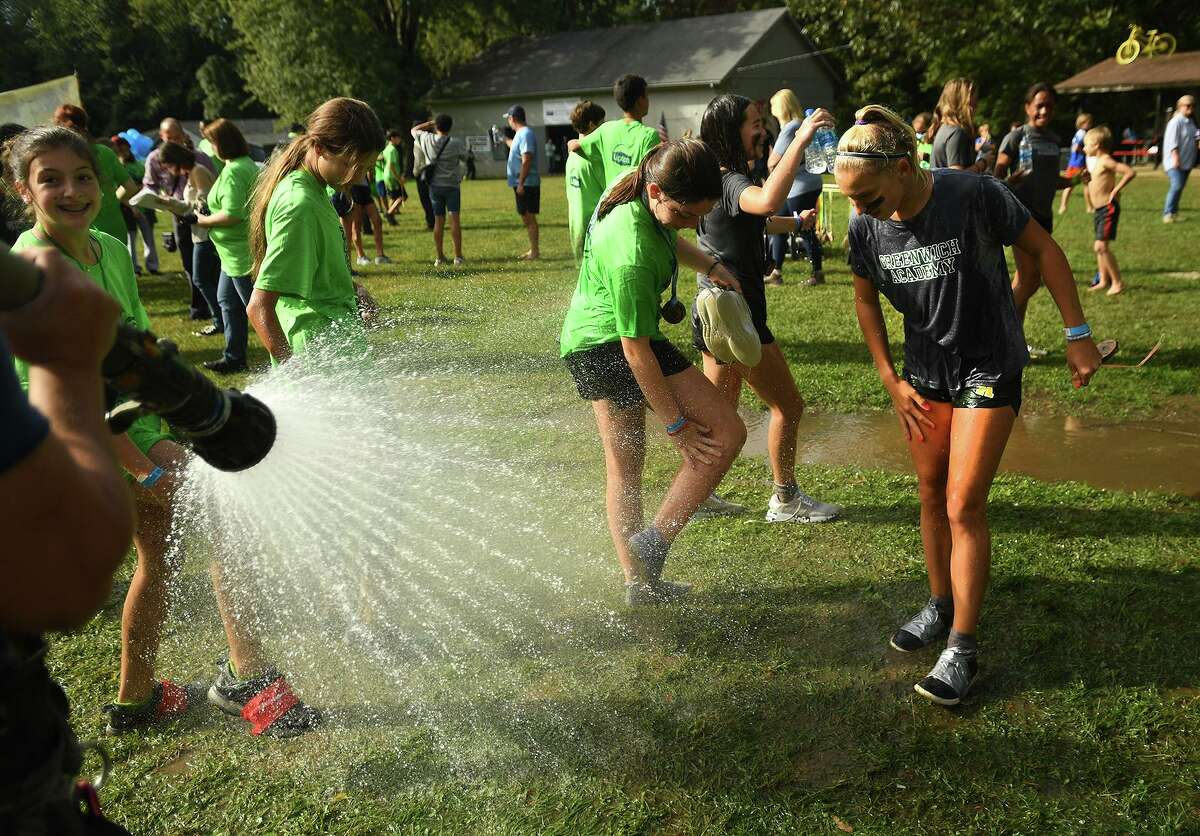 Runners hose off the mud with the assistance of the Greenwich Fire Department following the finish of the 9th Annual Muddy Up 5k run at Camp Simmons in Greenwich, Conn. on Sunday, October 3, 20i21.