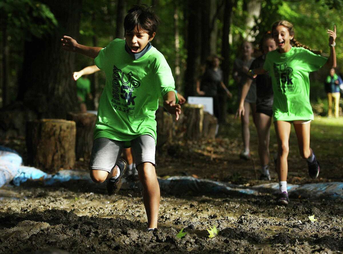 Runners cross the first of several mud pits during the 9th Annual Muddy Up 5k run put on by the Boys and Girls Club of Greenwich at Camp Simmons in Greenwich, Conn. on Sunday, October 3, 20i21.