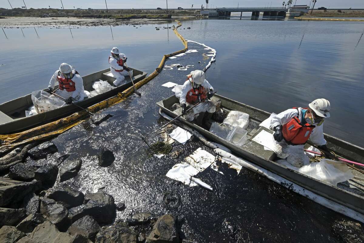 Clean-up contractors deploy skimmers and floating barriers known as booms to try to stop further oil crude incursion into the Talbert Marsh in Huntington Beach, Calif., Sunday, Oct. 3, 2021.