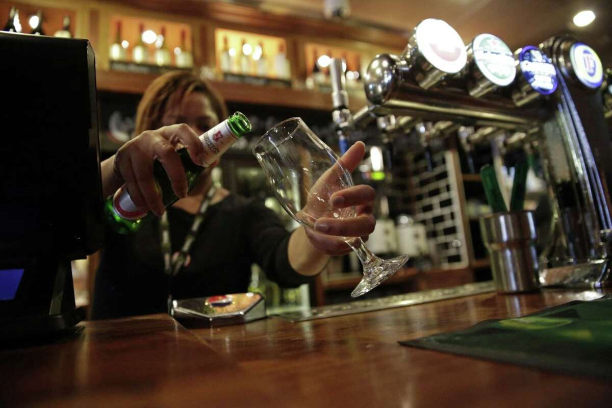 A JD Wetherspoon employee pours Becks lager from a bottle into a glass behind the bar at one of the company's pubs in London on Sept. 13, 2013.