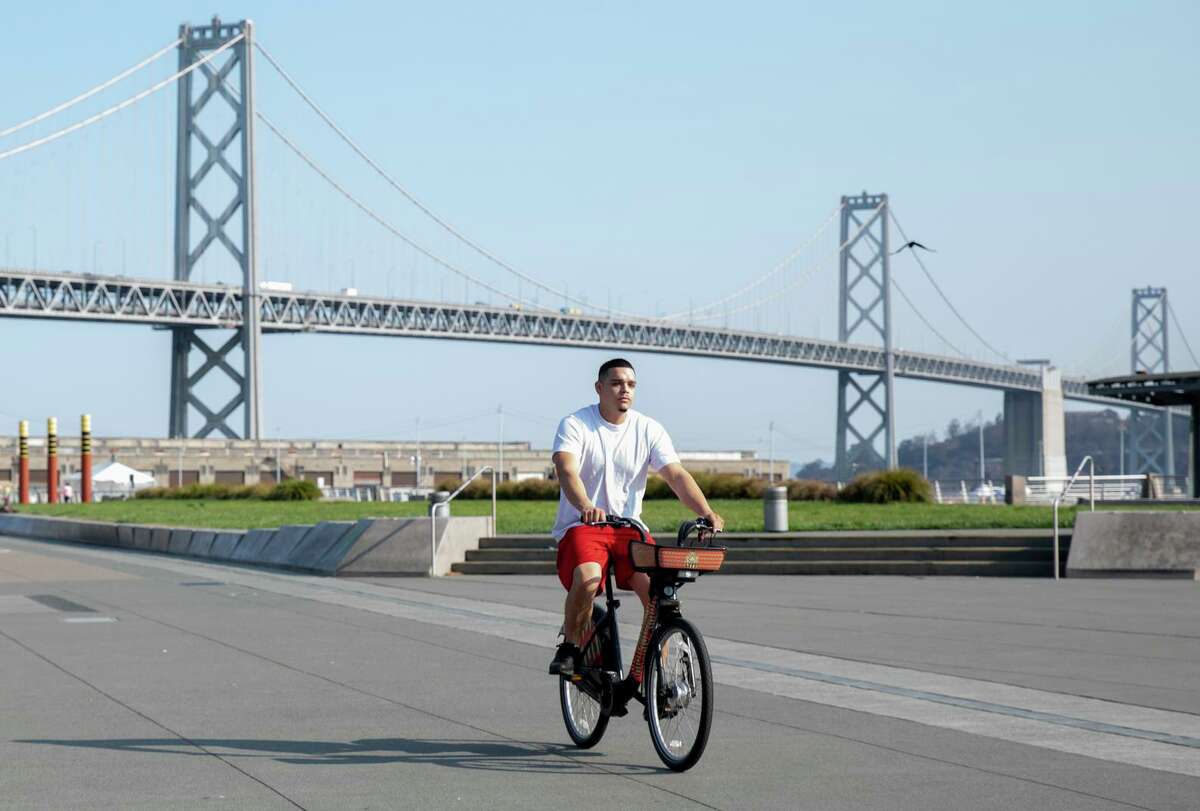 A person rides a Bay Wheels bike along the Embarcadero in San Francisco.