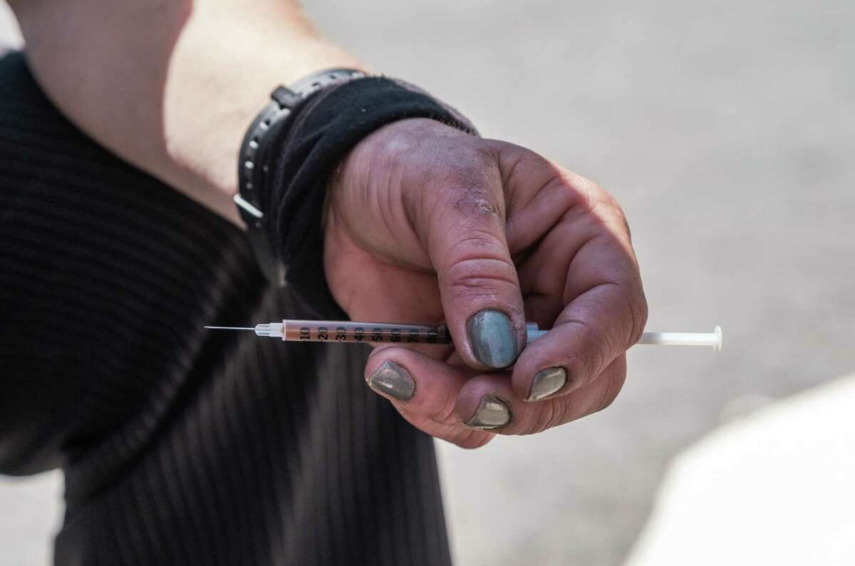 A heroin user prepares a needle before injecting near the Civic Center BART station.