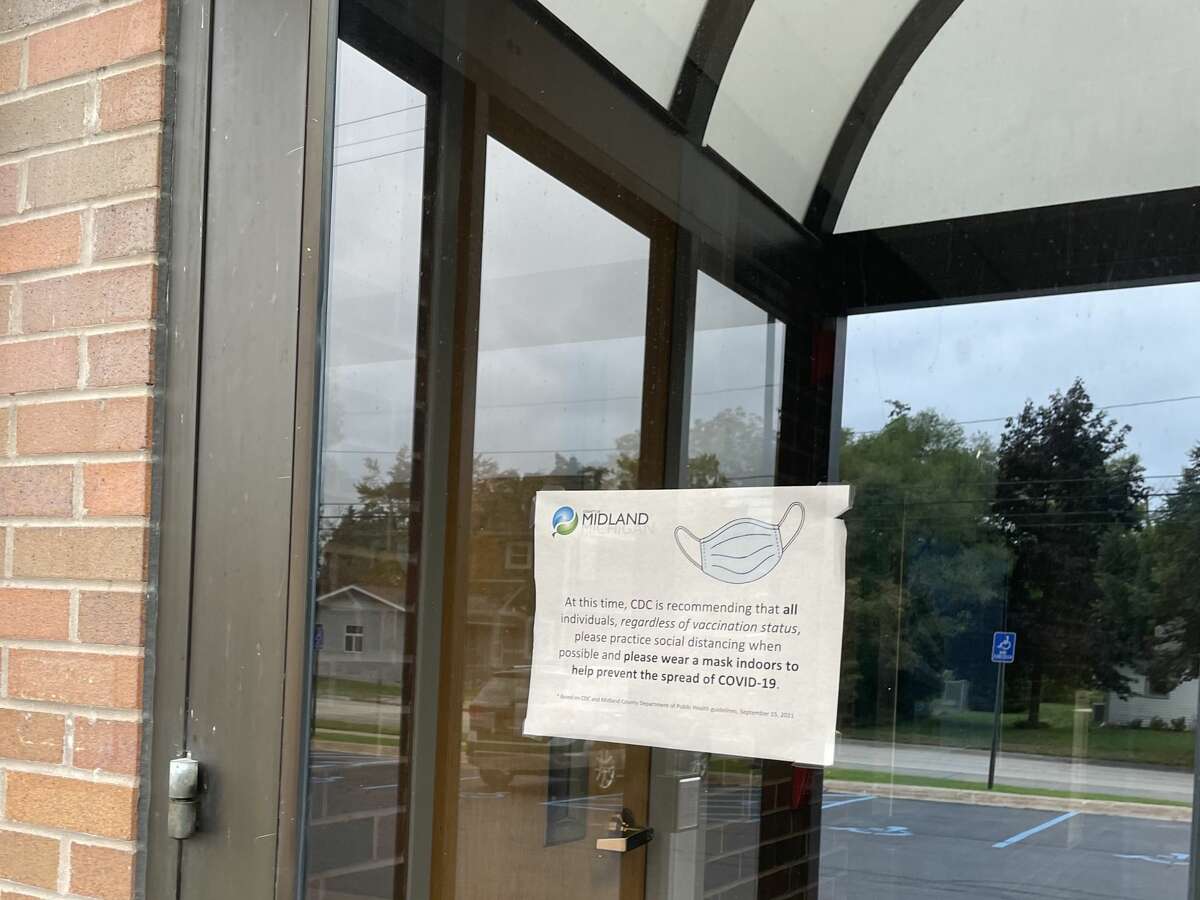 A sign encourages COVID-19 precautions, regardless of vaccination status, outside of the County Services building on Tuesday, Oct. 5. The Board of Commissioners regularly meet at the building, which is is located at 220 West Ellsworth Street in Midland. 