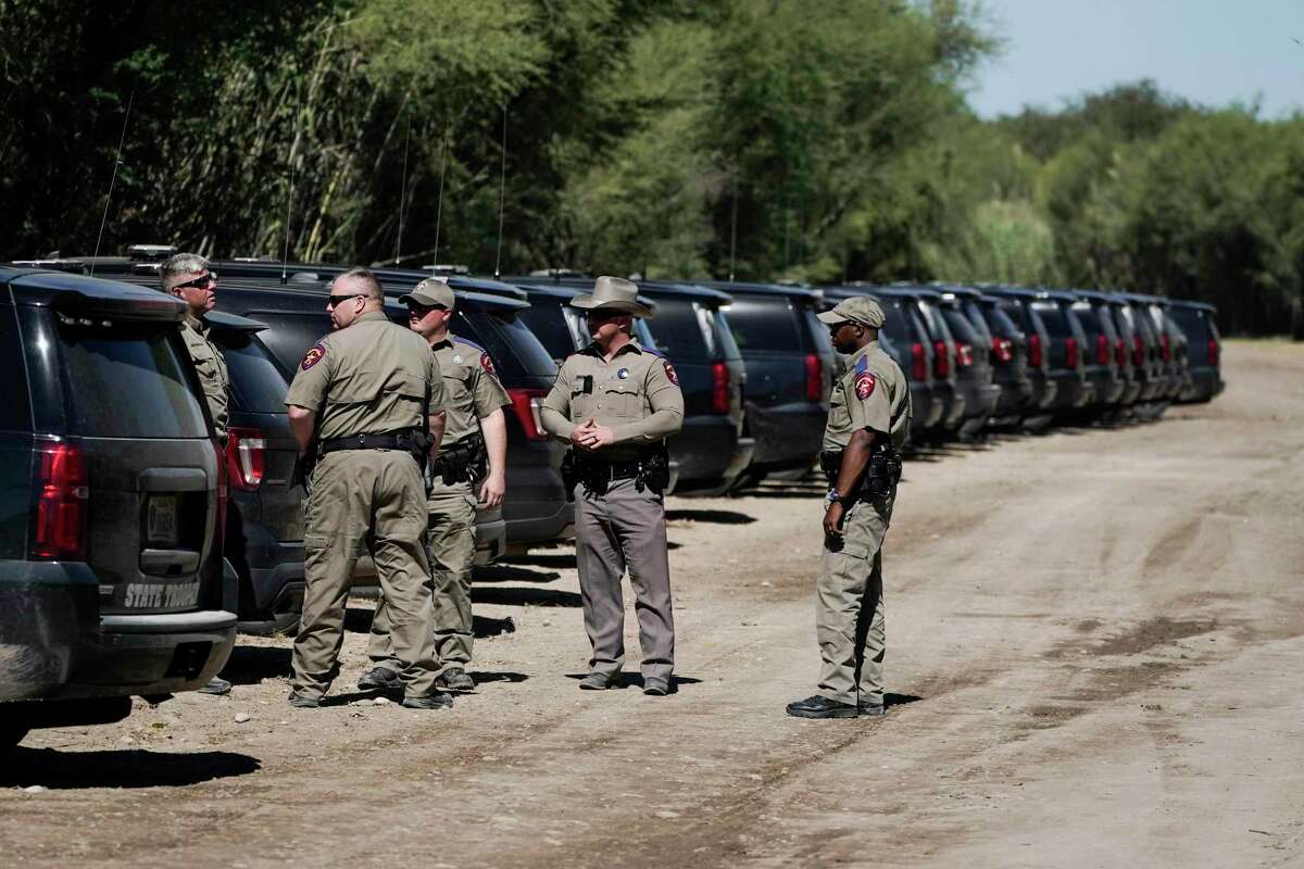 Texas Department of Public Safety officials stand near a lineup or vehicles parked near an encampment under the Del Rio International Bridge where migrants, many from Haiti, have been staying after crossing the Rio Grande, Thursday, Sept. 23, 2021, in Del Rio, Texas. (AP Photo/Julio Cortez)