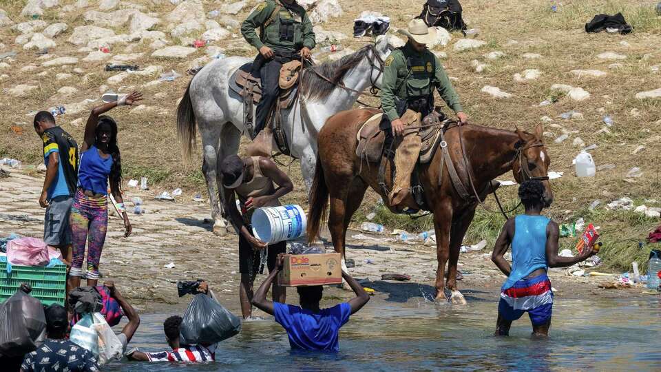 U.S. Border Patrol agents interact with Haitian immigrants on the bank of the Rio Grande in Del Rio, Texas, on Monday, Sept. 20, 2021, as seen from Ciudad Acuna, Mexico. (John Moore/Getty Images/TNS)