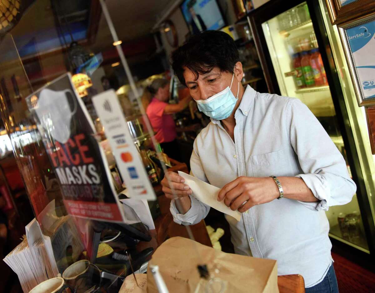 Manager John Montoya wears a mask while preparing a customer's order at Putnam Restaurant in Greenwich, Conn. in August 2021.