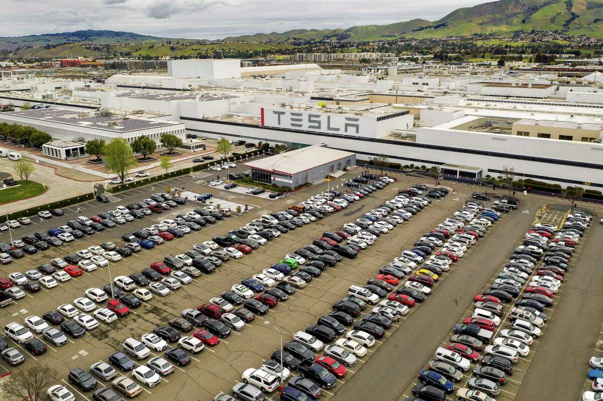 More Tesla layoffs loom as company will reportedly freeze hiring. Cars line a parking lot at Tesla’s Fremont, Calif., factory in 2020.