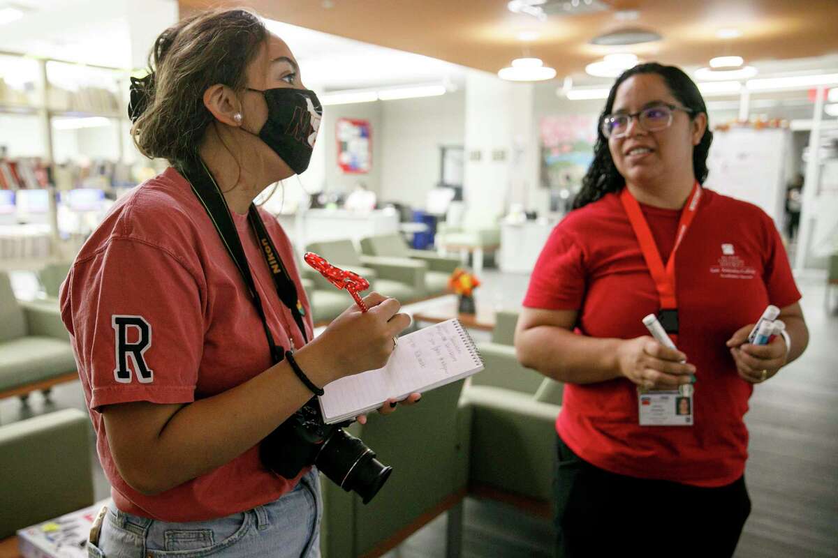 Ranger photographer Veronica Alcorta, left, takes notes as she talks to Crystal Escobales, an academic program specialist who was creating a sign in honor of National Tutoring Week in the Writing Center at San Antonio College on Wednesday. The Ranger is set to close in December after 95 years. Alcorta started working for it a week ago.