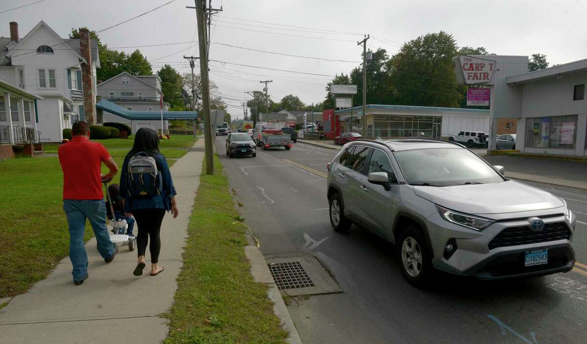 A couple walk with a baby on the sidewalk next to White Street. Danbury is seeking a $3 million state grant to add sidewalks and improve five intersections along White Street. The project area runs from Meadow Street to Cross Street. Thursday, October 7, 2021, Danbury, Conn.