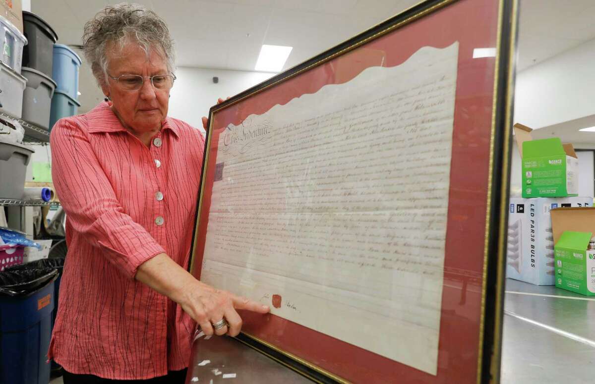 Karla Oubre, a 10-year volunteer of the Interfaith of The Woodlands’ Hand Me Up Shop, points out the well-conditioned wax seal on a 1823 bill of sale from England recently donated, Thursday, Oct. 7, 2021, in Spring. The 10-year volunteer used various genealogy sites to help track down the families of several antique book and items donated to The Woodlands non-profit.