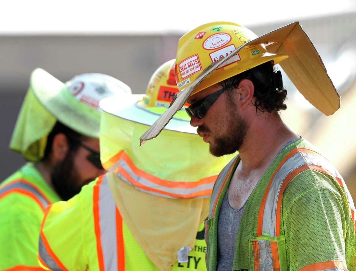 Reagan Fitts wears a safety hat with a custom sun visor he made from a cardboard box while working on the Texas 242 construction project, Thursday, Sept. 2, 2021, in Conroe. “Hey man, you do whatever works,” Fitts said. “Especially in his heat. Brutal. No shade.”