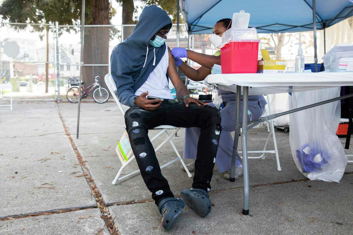 Alameda County Public Health nurse Emawayish Haile administers the Pfizer vaccine to 17-year-old Oakland Tech student Daylon Perkins at a vaccine clinic at Oakland Tech High School in Oakland in September.