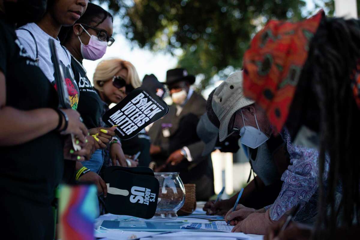 Members from the University of Houston Black Student Union sign in attendees of a rally against the redistricting efforts in Austin on Thursday, Oct. 7, 2021, at Emancipation Park in Houston, Texas.