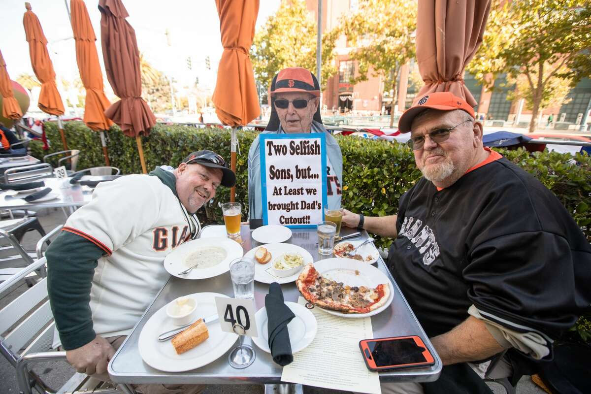 A cutout of Bert Crosthwaite, center, at the table with sons Ron, left, and Jim while they enjoy a pre-game meal at MoMo's. The Crosthwaites, from the Sacramento area, love to go to Giants games, but Bert could not make it to this game. Instead, his sons brought a cutout that was inside Oracle Park during the pandemic season of 2020.