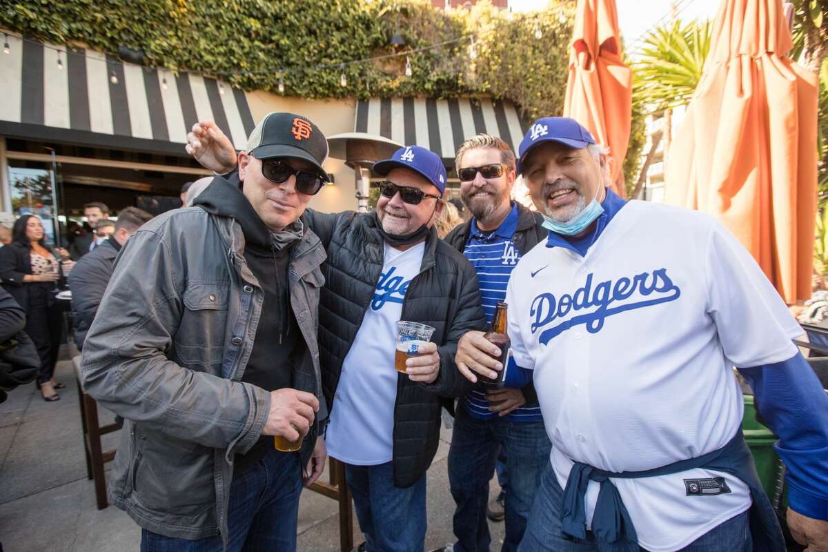(Left to Right) San Francisco Giants fan Chris Sammet chats with Los Angeles Dodgers fans Dan Cota, Steve Quinn and Henry Eshom at Momo Sports Bar and Restaurant across from Oracle Park in San Francisco on October 8, 2021.
