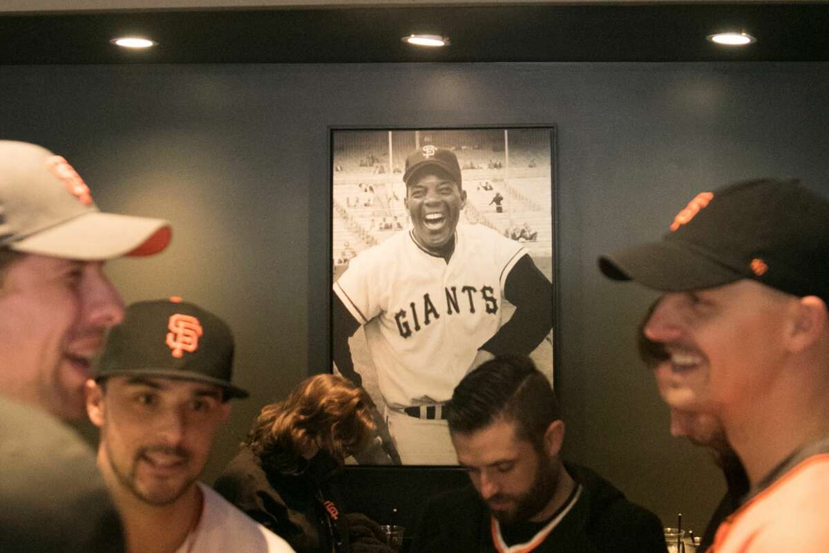 San Francisco Giants fans share a laugh under a picture of Giants Hall of Famer Willie Mays at MoMo's, a sports bar and restaurant that sits across the street from Oracle Park in San Francisco, on Oct. 8, 2021.