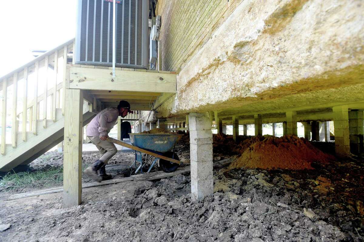 A worker moves cartloads of dirt beneath a raised home as the ground surrounding it is leveled. Several homes in Bevil Oaks have been raised, with many more scheduled for elevation work, following grant money to do the work as protection against future flood damage. Residents in the small city straddling the Jefferson and Hardin County line were among some of the hardest hit during Tropical Storm Harvey. Photo made Wednesday, October 6, 2021 Kim Brent/The Enterprise