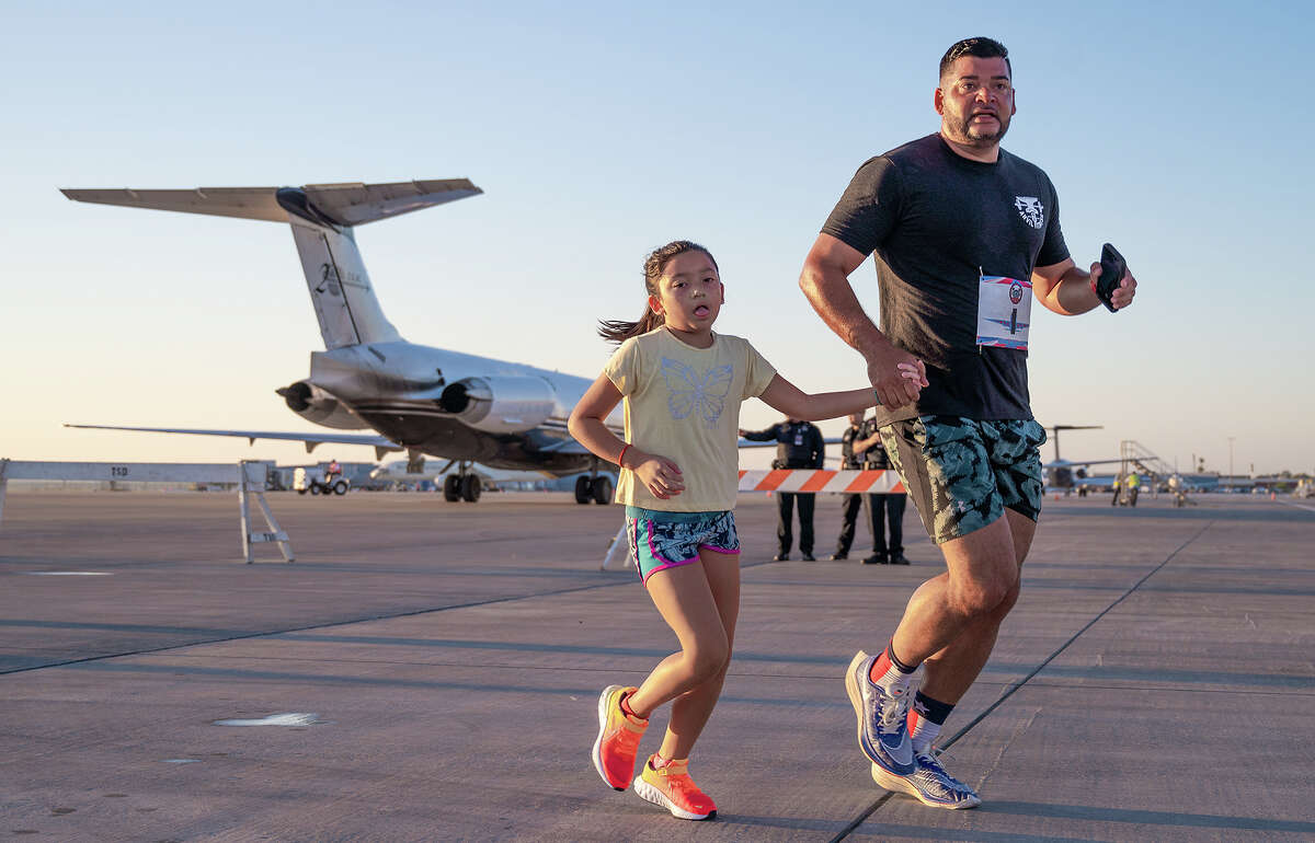 Runners Jorge Adrian and Phoenix Adrian pass the last stretch of the Runway Run 1k race, Saturday, Oct. 9, 2021 outisde the Signature Flight Support building.