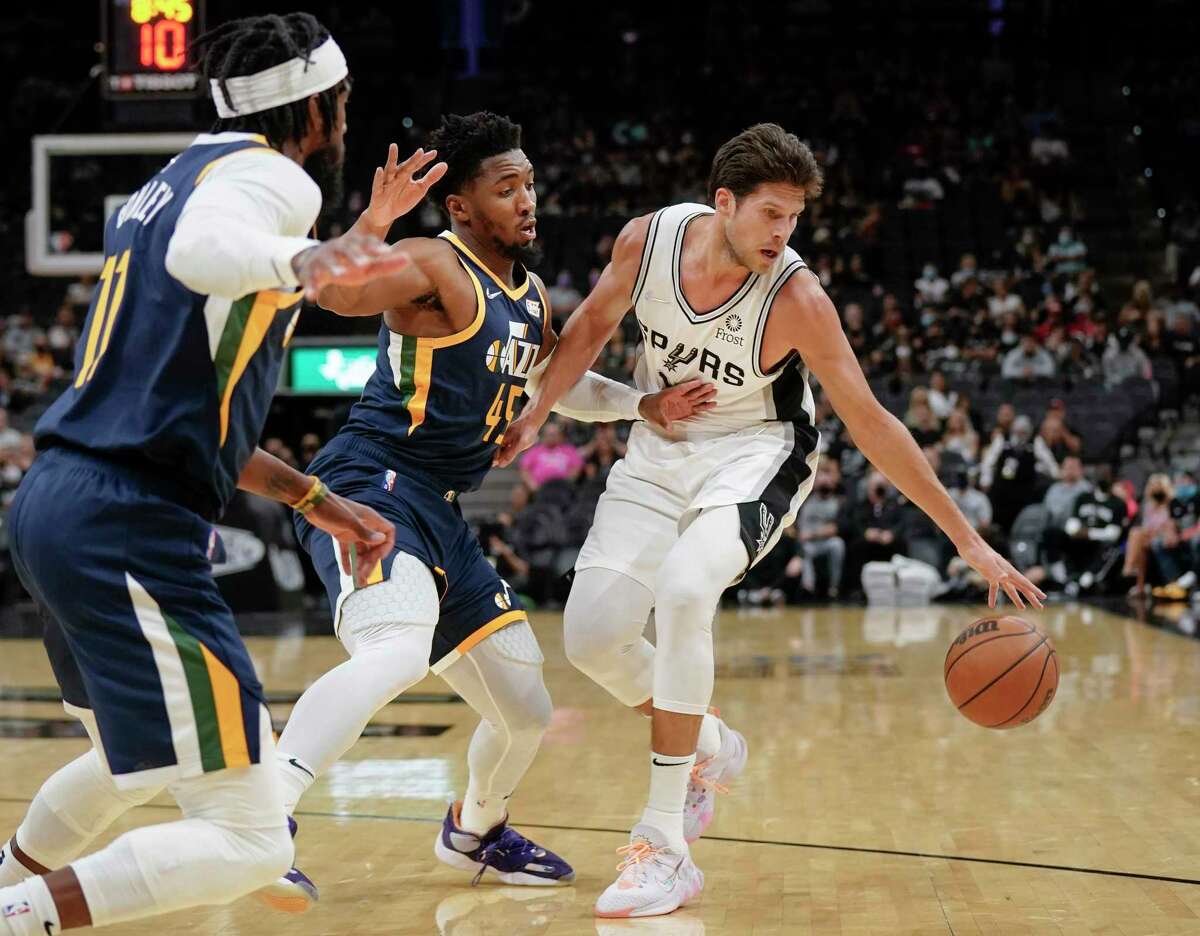 San Antonio Spurs' Doug McDermott, right, drives against Utah Jazz's Donovan Mitchell (45) and Mike Conley during the first half of a preseason NBA basketball game on Monday, Oct. 4, 2021, in San Antonio. (AP Photo/Darren Abate)