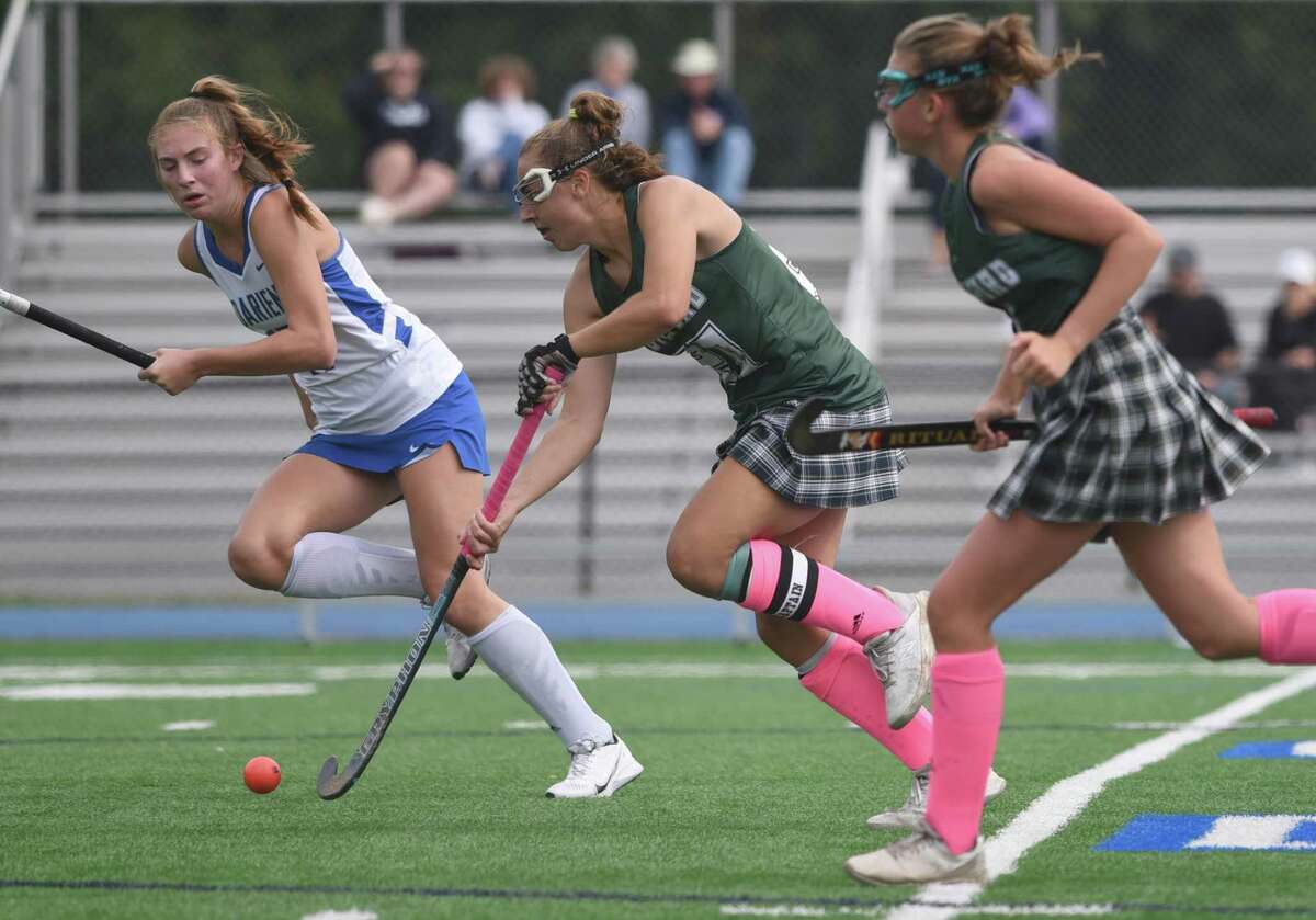 Guilford's Maddie Epke (20) races through the midfield as Darien's Morgan Massey gets back to defend during a field hockey game in Darien on Saturday, Oct. 9, 2021.